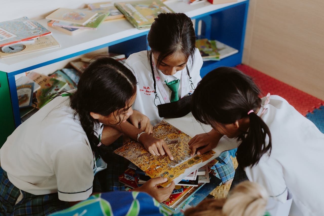 Group of children engaging in collaborative learning in a school setting, focused on a book.